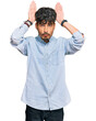 © Krakenimages.com - Young hispanic man wearing casual clothes doing bunny ears gesture with hands palms looking cynical and skeptical. easter rabbit concept.
