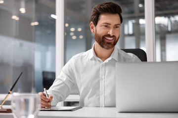 Canvas Print - Portrait of smiling man working with laptop in office, space for text. Lawyer, businessman, accountant or manager