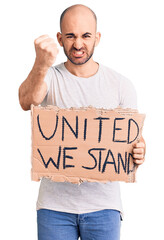 Poster - Young handsome man holding united we stand banner annoyed and frustrated shouting with anger, yelling crazy with anger and hand raised