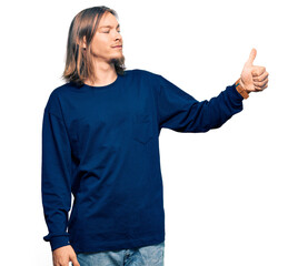 Sticker - Handsome caucasian man with long hair wearing casual winter sweater looking proud, smiling doing thumbs up gesture to the side