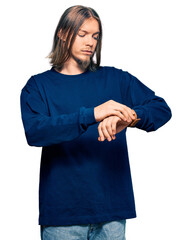 Poster - Handsome caucasian man with long hair wearing casual winter sweater checking the time on wrist watch, relaxed and confident