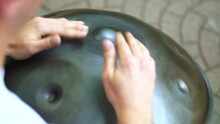 A Man Plays Hang In The Park. The Street Musician Plays The Tank Drum. Musician Plays The Handpan. Musician Plays The Steel Tongue Drum On A Bench In The Park.