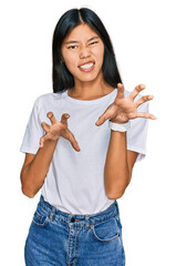 Sticker - Beautiful young asian woman wearing casual white t shirt smiling funny doing claw gesture as cat, aggressive and sexy expression