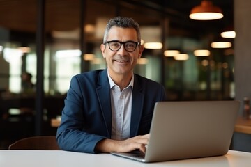 Wall Mural - Happy busy middle aged business man ceo wearing suit sitting at desk in office using laptop. Mature businessman professional executive manager working on computer corporate technology at workplace 