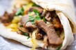 freshly made shawarma on pita bread with a bite taken, close-up