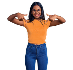 Wall Mural - Young indian girl wearing casual clothes and glasses looking confident with smile on face, pointing oneself with fingers proud and happy.