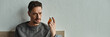 pensive man looking at bottle with medication while sitting in bedroom, treatment plan banner