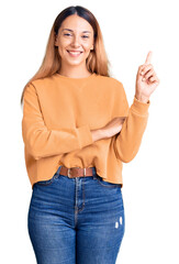 Sticker - Beautiful young woman wearing casual clothes with a big smile on face, pointing with hand and finger to the side looking at the camera.