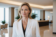 © EliteLensCraftImages - female middle age white hotel receptionist or manager standing in lobby with reception. welcoming guests, offering services or checkin. tourism and travel concept.
