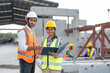 © Supachai - Asian male and female civil engineers wearing vest and helmet safety discussing on document at factory making precast concrete wall in construction site.