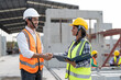© Supachai - Asian male and female civil engineers wearing vest and helmet safety handshake to work successfully at factory making precast concrete wall in construction site.