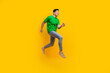 © deagreez - Full length photo of optimistic pleasant man dressed green t-shirt look at sale empty space running isolated on yellow color background