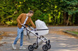 © Ivan - Young father strolling a sleeping baby in pram on city street