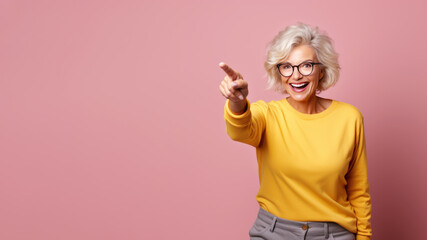 Wall Mural - Happy senior blonde woman point her finger at copy space for promotion