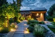 Modern house exterior at night with illuminated garden pathway and landscaping