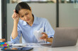 © Songsak C - An Asian businesswoman is stressed over her expense bill.