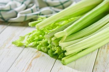 Wall Mural - fresh green celery stalks on a white wooden table.