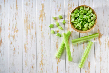 Wall Mural - Cut fresh green celery in a white wooden table, flat lay. Space for text.