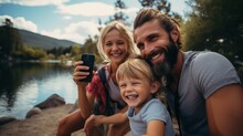 Cheerful Family Taking Selfie Through Mobile Phone By Lake