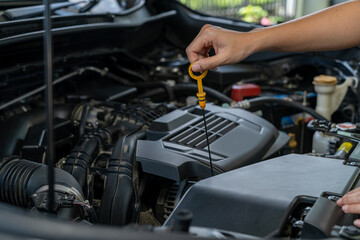 A young woman checking the car engine oil by herself