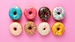 © Anna - a group of doughnuts with sprinkles arranged in a row on a pink background, top view.