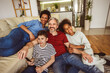 © Mediteraneo - Young family watching TV together at home and having fun together.