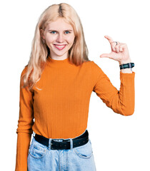 Canvas Print - Young caucasian woman wearing casual clothes smiling and confident gesturing with hand doing small size sign with fingers looking and the camera. measure concept.