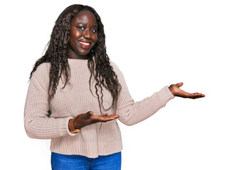 Wall Mural - Young african woman wearing wool winter sweater inviting to enter smiling natural with open hand