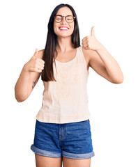 Poster - Young beautiful caucasian woman wearing casual clothes and glasses success sign doing positive gesture with hand, thumbs up smiling and happy. cheerful expression and winner gesture.