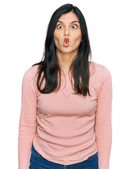 Wall Mural - Young hispanic woman wearing casual clothes making fish face with lips, crazy and comical gesture. funny expression.