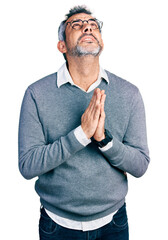 Poster - Middle age hispanic with grey hair wearing glasses begging and praying with hands together with hope expression on face very emotional and worried. begging.