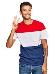 Wall Mural - Young handsome african american man wearing casual clothes showing and pointing up with fingers number three while smiling confident and happy.