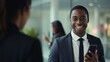 © pvl0707 - dynamic essence of a smiling young African American businessman engaged in a professional mobile call, showcasing the modern, energetic vibe of corporate communication in an office setting