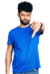 Canvas Print - Young arab man with beard wearing casual blue t shirt looking unhappy and angry showing rejection and negative with thumbs down gesture. bad expression.