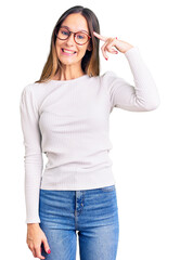 Wall Mural - Beautiful brunette young woman wearing casual white sweater and glasses smiling pointing to head with one finger, great idea or thought, good memory