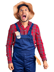 Sticker - Handsome latin american young man weaing handyman uniform angry and mad screaming frustrated and furious, shouting with anger. rage and aggressive concept.