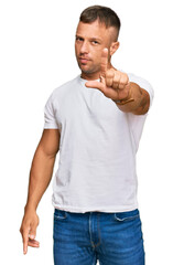 Wall Mural - Handsome muscle man wearing casual white tshirt pointing with finger up and angry expression, showing no gesture