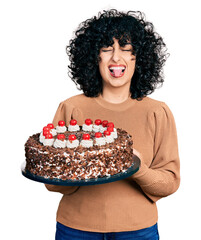 Poster - Young hispanic couple celebrating birthday with cake sticking tongue out happy with funny expression.