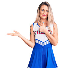 Poster - Young beautiful blonde woman wearing cheerleader uniform showing palm hand and doing ok gesture with thumbs up, smiling happy and cheerful