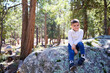 © joescarnici - A young boy hangs out in the forest wearing a sweater