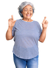 Poster - Senior woman with gray hair wearing casual striped clothes gesturing finger crossed smiling with hope and eyes closed. luck and superstitious concept.