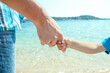 © Kostia - A Hands of a happy parent and child in nature by the sea on a journey background