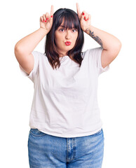 Poster - Young plus size woman wearing casual clothes doing funny gesture with finger over head as bull horns