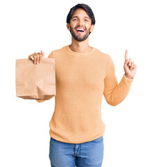 Poster - Handsome hispanic man holding take away paper bag surprised with an idea or question pointing finger with happy face, number one