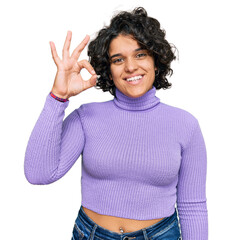 Canvas Print - Young hispanic woman with curly hair wearing casual clothes smiling positive doing ok sign with hand and fingers. successful expression.