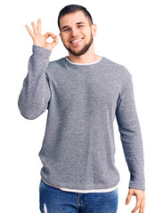 Wall Mural - Young handsome man wearing casual sweater smiling positive doing ok sign with hand and fingers. successful expression.