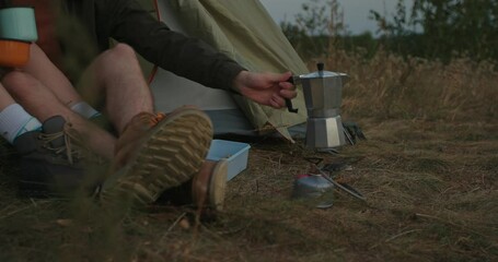 Wall Mural - Close-up of the legs of a couple in love sitting near a tent while camping in the mountains.