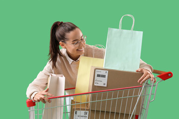 Sticker - Female seller with bags and parcels in shopping cart on green background