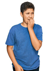 Poster - Teenager hispanic boy wearing casual clothes looking stressed and nervous with hands on mouth biting nails. anxiety problem.