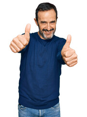 Middle age hispanic man wearing casual clothes approving doing positive gesture with hand, thumbs up smiling and happy for success. winner gesture.